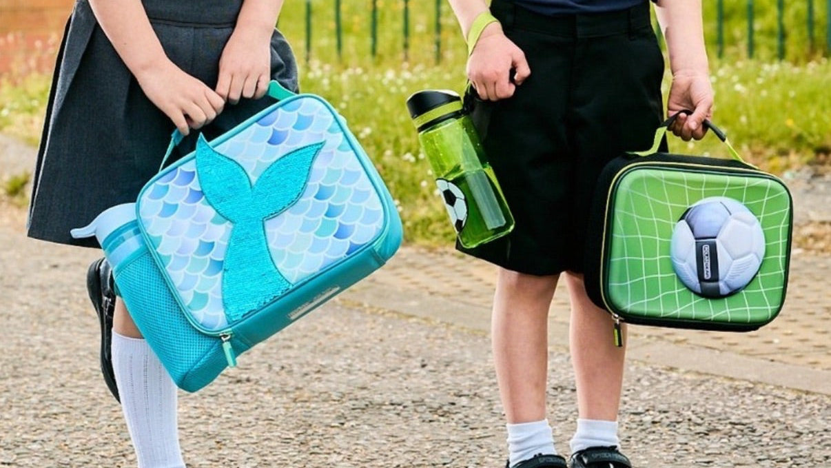 Two children holding lunch bags with a school setting in the background
